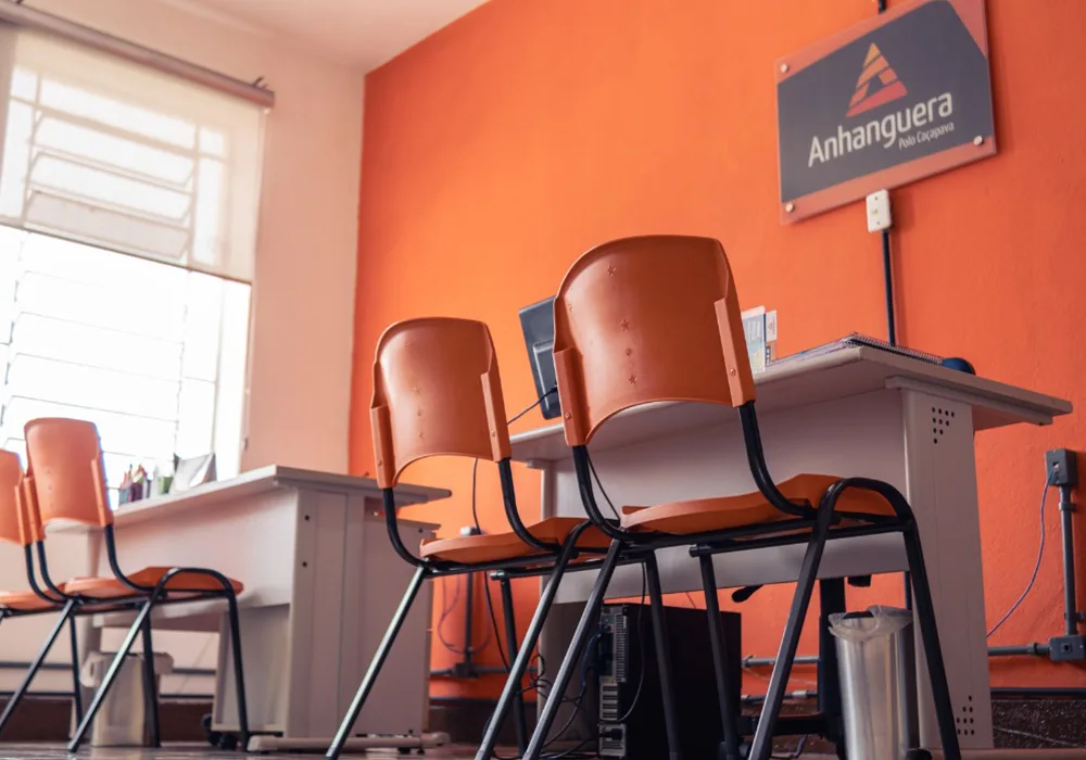 Sala de atendimento do Polo Anhanguera Caçapava com cadeiras laranja e parede laranja com logotipo.